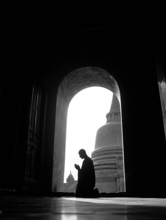 A monk kneels in prayer, silhouetted against a dome, framed by the archway of a tranquil temple, capturing the stillness of the moment.の素材