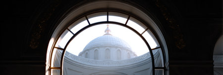 Soft light highlights the intricate design of a dome seen through an arched window, offering a glimpse of architectural beauty and tranquility.の素材
