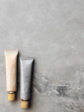 Two tubes of adhesive for stone and tile are positioned on a plain surface, showing different colors and materials in a modern layout.の素材