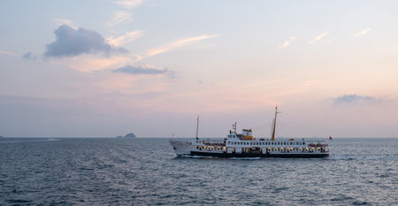 A ferry travels across the Bosphorus strait at sunset, with gentle waves and a colorful sky reflecting the end of the day.の写真素材