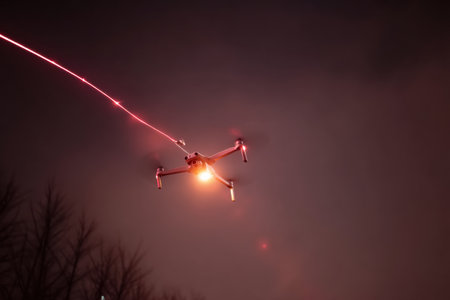 A drone navigates through the night sky, utilizing red alert path lights to guide its delivery. The upper third of the view is faded for focus.の素材