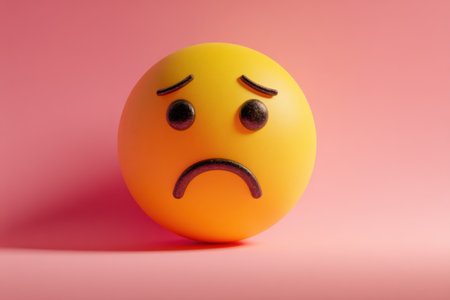 A sad emoji features a frowning expression and dark eyes set against a softly colored pink background, creating a contrast that highlights its emotions.の素材
