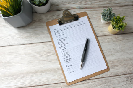 Clipboard holds a detailed freezer inventory checklist, accompanied by a pen and small plants, placed on a wooden countertop in a contemporary kitchen.の素材
