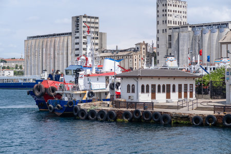 Boats are docked along the Bosphorus waterfront beside old buildings, illustrating vibrant city life and maritime activities in Istanbul during a sunny day.の写真素材
