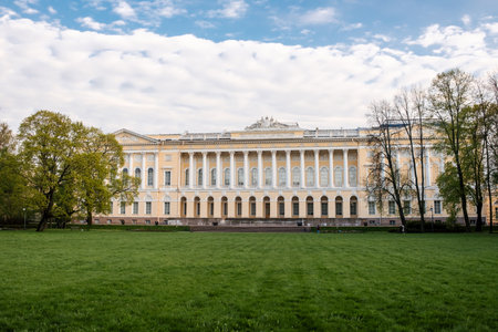 A stunning palace showcases classic architecture surrounded by vibrant greenery under a partly cloudy sky. Visitors can enjoy the serene atmosphere.の写真素材