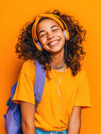 A cheerful student poses against a vibrant orange background, wearing headphones and a bright outfit, radiating joy and readiness for the new school year.の素材