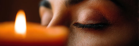 Candlelight flickers softly as a person meditates with closed eyes, fostering tranquility and focus during a calming mindfulness practice in a serene location.の素材