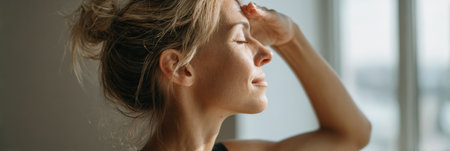 A woman engages in eye yoga, enjoying the calming atmosphere of her minimalist home illuminated by soft, natural light from the window.の素材