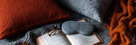Experience the warmth of an autumn interior featuring a sleeping mask, an open book, and soft bedding, creating a peaceful atmosphere for relaxation.の素材