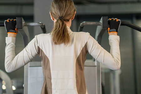 A determined woman works on her strength training with pull-ups at a local gym during the early...