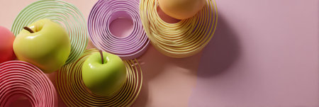 Colorful 3D spirals resembling fruit rest on a smooth pastel surface, featuring gradient shadows that enhance their lively colors and design.の素材
