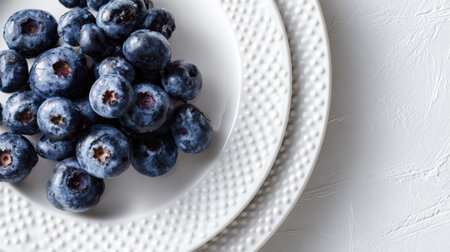 Delicious blueberries arranged on a stylish white ceramic plate with a unique dotted texture, ideal for enhancing any meal presentation.の素材