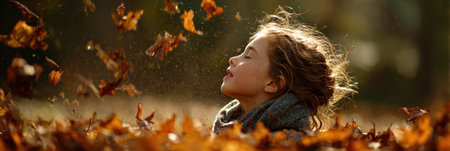Young girl sneezes joyfully as she plays in a vibrant pile of autumn leaves under clear skies, capturing the essence of a bright fall day.の素材