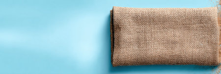 Display of eco-friendly packaging wrapped in burlap cloth set on a smooth sky-blue background, highlighting sustainable practices and natural materialsの素材