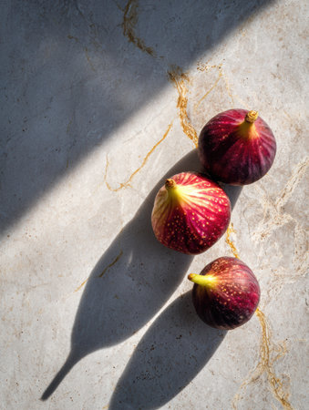 Fresh figs are placed on a smooth stone slab, casting long shadows that enhance their vibrant colors and textures, creating a captivating visual display.の素材