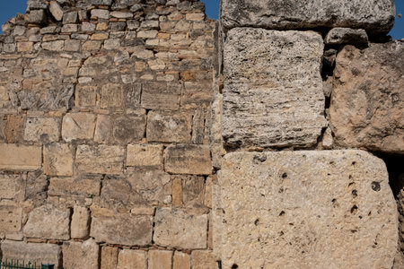 Visitors admire the ancient stone walls of Pamukkale, highlighting the intricate patterns and textures under the warm sun.の写真素材