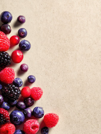 A vibrant mix of raspberries, blueberries, and blackberries rests on soft paper, with gentle shadows highlighting their freshness.の素材