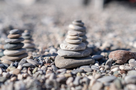 Beautifully arranged stones create artistic towers on a tranquil pebbled beach, emphasizing harmony...
