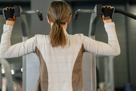 Individual performs pull ups at a modern indoor gym, working on upper body strength and endurance in...