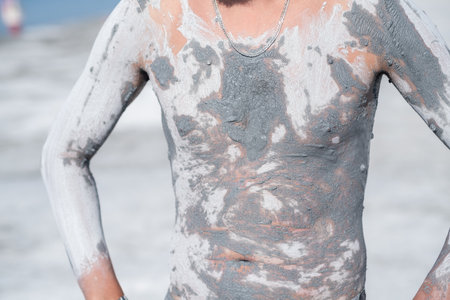Person enjoys a therapeutic experience by covering their body with clay mud for skin benefits at a...