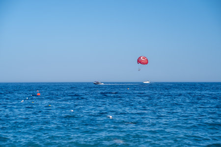 Participants enjoy parasailing above turquoise waters, experiencing an exhilarating view of the ocean and nearby boats on a sunny day.の写真素材