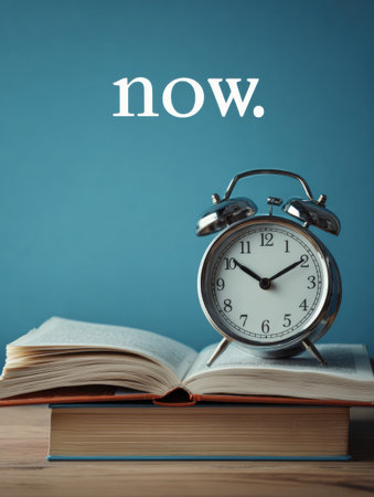 Hands of a clock point to now while an open book rests beside it, representing the significance of the present moment and personal growth.の素材