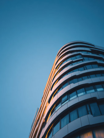 Curved building facade displays sleek architecture with a digital banner slot, under an expansive clear sky, reflecting modern urban design during daytime.の素材