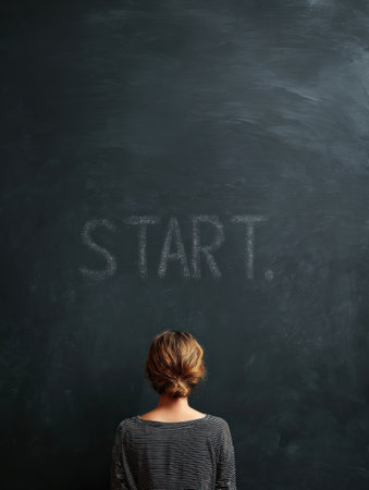 A student stands in front of a chalkboard, contemplating the word start. The atmosphere is calm, encouraging learning and motivation.の素材