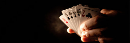 A player reveals a winning poker hand featuring an ace high during an intense late-night card game, illuminated by dramatic lighting for added effect.の素材