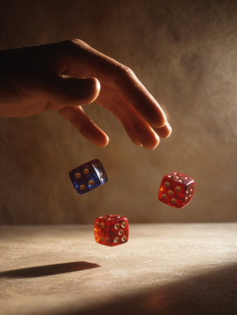 Colorful dice are tossed mid-air from a hand above a shadowed surface, capturing a moment filled with anticipation and excitement typical of game nights.の素材