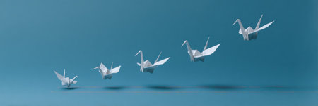 Paper origami cranes soar gracefully over a chart depicting key learning milestones, symbolizing growth and development through education.の素材