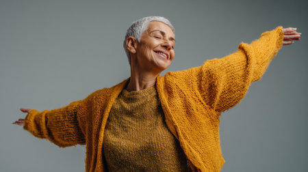 Senior woman dances with joy, embracing her individuality and celebrating personal growth in a tranquil indoor space, radiating happiness and confidence.の素材