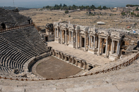Visitors admire the impressive stone structure of an ancient theater at Pamukkale, surrounded by...