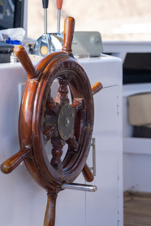 Steering wheel mounted on a boats cabin wall showcases craftsmanship and nautical decor, illuminated...