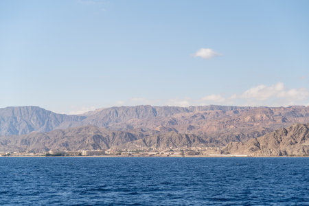 Spectacular mountainous landscape merges with tranquil waters, showcasing a coastal settlement under...