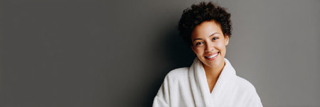 Relaxed woman wearing a robe smiles warmly after a dermatology appointment, enjoying a peaceful atmosphere in a calming spa setting.の素材