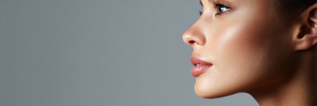 Soft lighting enhances the radiant skin texture and natural glow, emphasizing open skin pores and facial contours against a minimalistic backdrop.の素材