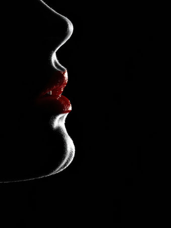 A womans silhouette stands out with luminous lipstick, creating a striking contrast against the darkness, emphasizing beauty and artistry in simplicity.の素材