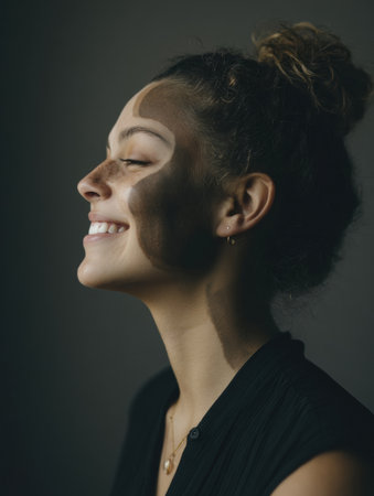 A woman exhibits a joyful expression as she dons artistic face paint, highlighting unique patterns that reflect creativity and personality during an art event.の素材