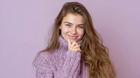 A young woman with long, wavy hair smiles gently while playfully touching her face.の素材