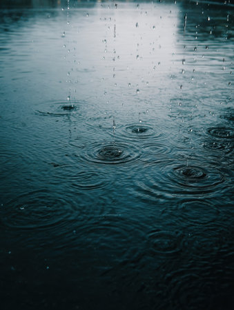 Raindrops create ripples in a still pond, reflecting the soft light of dusk, enhancing the tranquil atmosphere of the serene natural environment.の素材