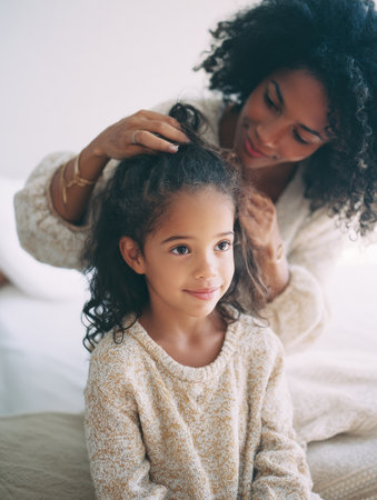 In a warm and inviting setting, a mother carefully braids her daughters hair, creating a moment of bonding and creativity at home.の素材