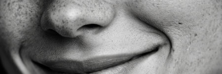 Detailed view of a smiling face showcasing unique skin texture and natural grain, presented in a monochrome style emphasizing facial features.の素材