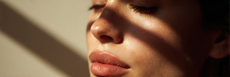 Soft sunlight reflects off the face, enhancing the natural features with gentle highlights while a light background adds to the serene atmosphere.の素材