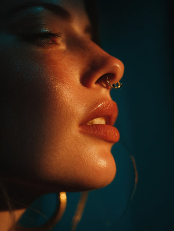 Soft light highlights the facial features of a person with a septum piercing, capturing details in the lips and skin. A calm, intimate atmosphere is present.の素材