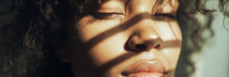 A womans face is half-lit, the other half in soft shadow, creating a thought-provoking contrast in a serene atmosphere.の素材