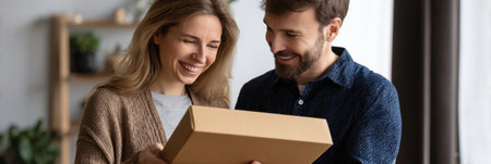 Joyful couple opens a cardboard package together in their cozy living room, sharing smiles and excitement over the surprise inside.の素材