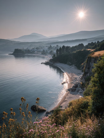 Soft light filters over a tranquil beach as waves lap at the shore, surrounded by lush greenery and distant mountains in the early morning light.の素材