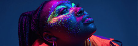 A model showcases vibrant glow in the dark makeup with colorful glitter in a dark studio setting, highlighting artistic expression and creativity.の素材