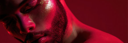 A model showcases intricate makeup with shimmering details under vibrant red lighting, embodying artistic expression in a studio setting.の素材